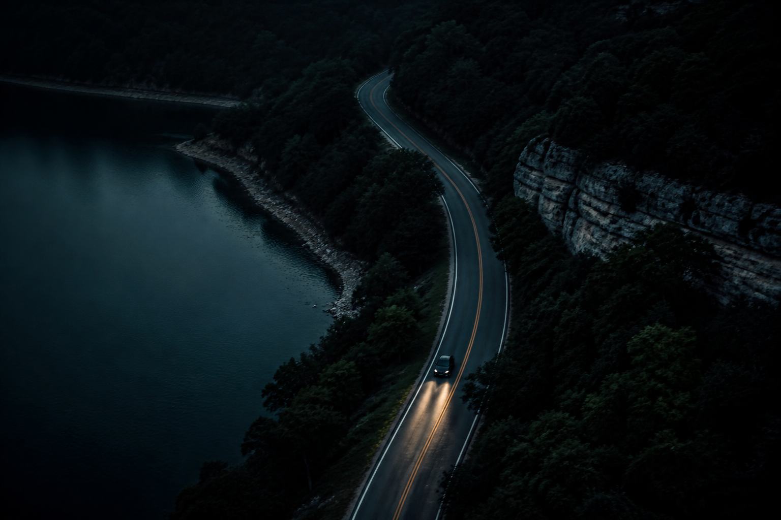 Placeholder still: aerial dusk view of Lime Creek Road along the water, headlights on the curve.
